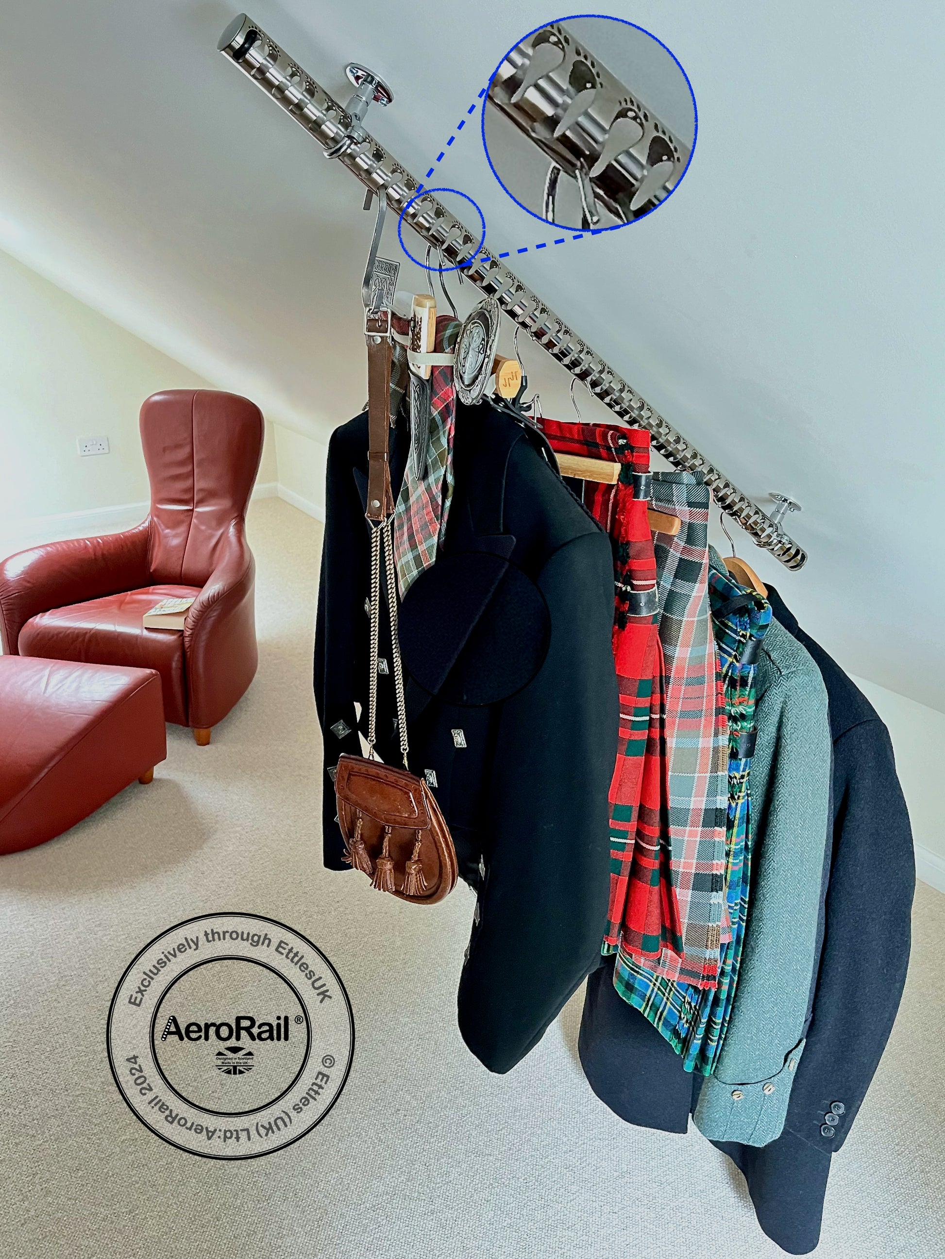 AeroRail clothing rack on an attic ceiling with jackets and kilts in a room with a red chair and beige carpet.